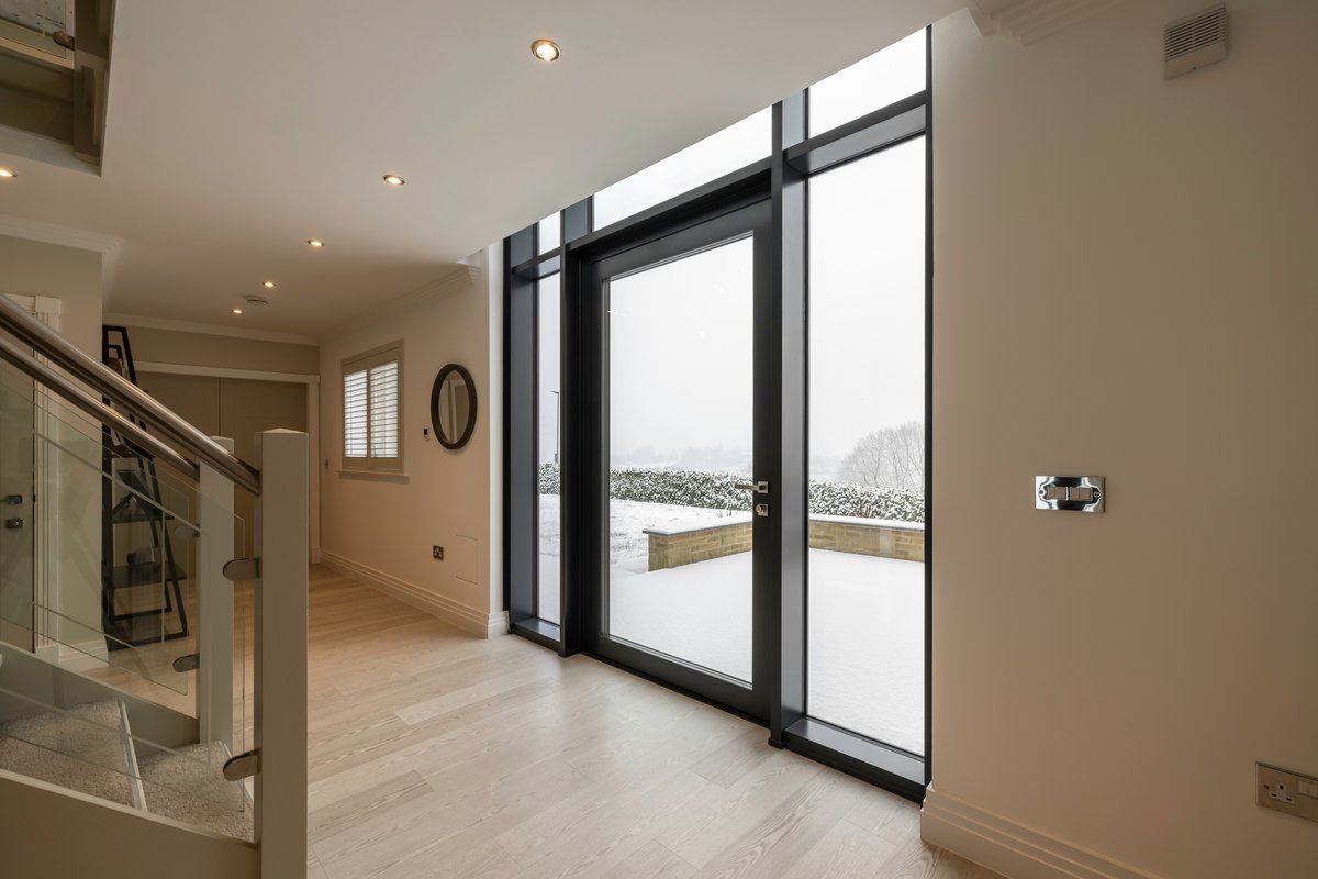 Oversized entrance door with full-height sidelights overlooking a snowy landscape