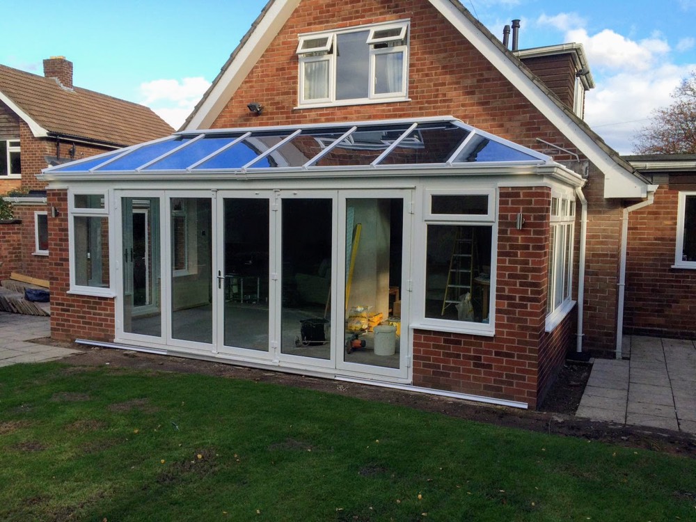 Bespoke orangery extension with blue-tinted glass roof on a brick property