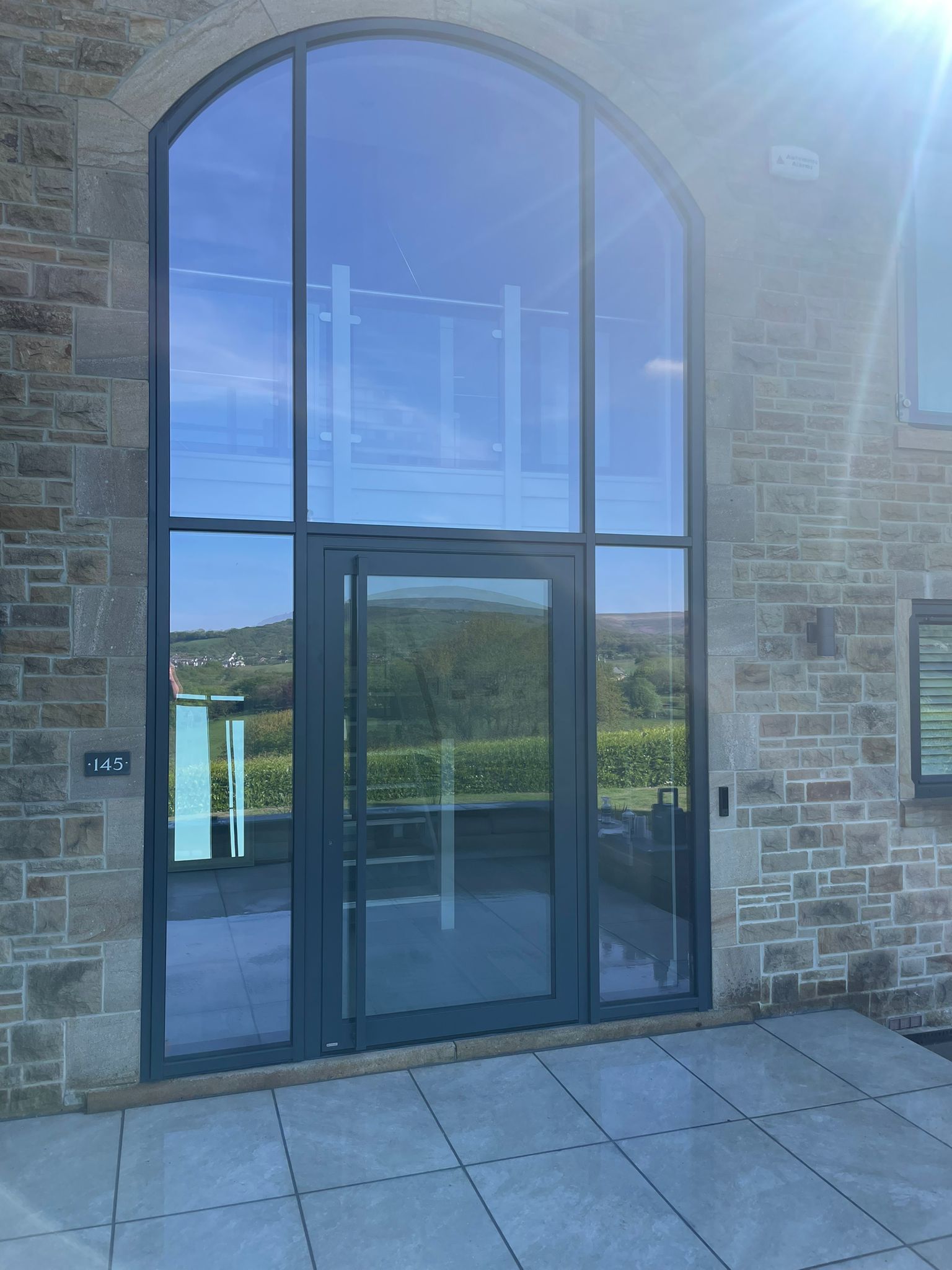 Bespoke aluminium glazing with arched fanlight on a stone-built home