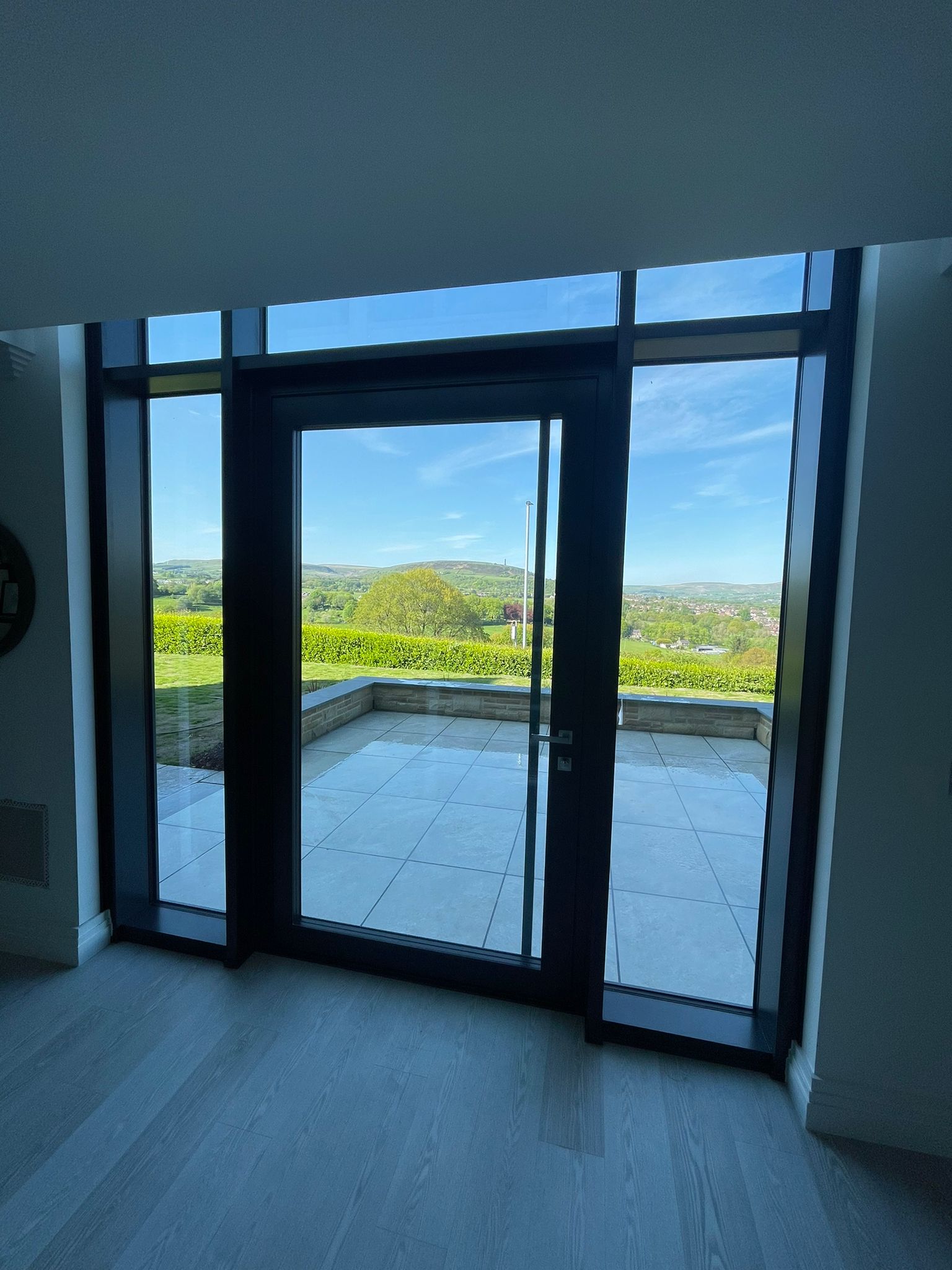Full-height aluminium structural glazing with terrace door and countryside views
