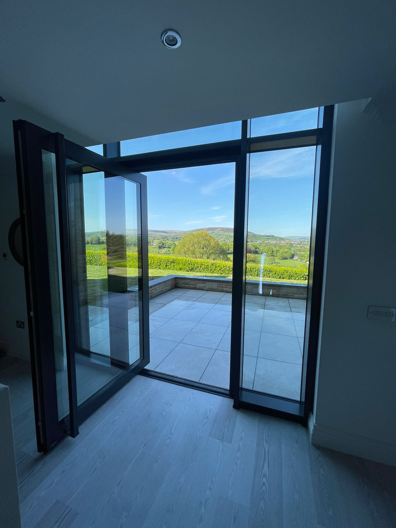 Reynaers CW 50 floor-to-ceiling aluminium curtain wall opening onto a paved terrace with countryside view